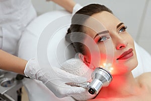 Facial Beauty Treatment. Woman Doing Red Led Light Therapy