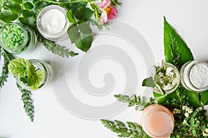 Facial body cosmetic products, leaves and flowers blossom on white desktop background whith copy space. spring skin care layout,