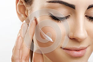 Facial Care. Female Applying Cream.Portrait Of  Young Woman With Cosmetic Cream On Skin. Closeup Of Beautiful Girl With Beauty