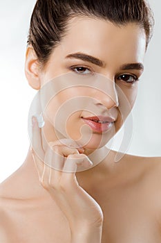 Facial Care. Female Applying Cream and Smiling. Portrait Of Young Woman With Cosmetic Cream On Skin.