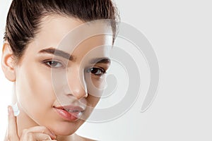 Facial Care. Female Applying Cream and Smiling. Portrait Of Young Woman With Cosmetic Cream On Skin.