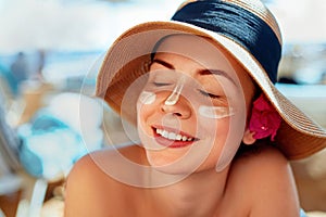 Facial Care. Female Applying Sun Cream and Smiling. Beauty Face. Portrait Of Young Woman in hat Smear Moisturizing