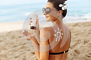 Facial Care. Young  Female Holding Bottle Sun Cream and  Applying on Face Smiling. Beauty Face.  Portrait Of Young Woman in hat Sm