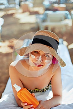 Facial Care. Young Female Holding Bottle Sun Cream and Applying on Face Smiling. Beauty Face.