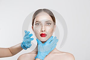 Facial cosmetic plastic surgery. Doctor surgeon hand in glove draw wrinkle lines on Woman face isolated white background.