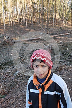 Facial expression of embarrassment or agitation. Autistic child looking into the camera. Backgrounds a felled part of the forest.
