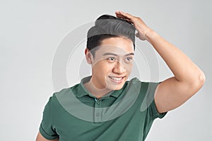 Facial expression. Portrait of a delighted good looking handsome man smiling to you while fixing his hair