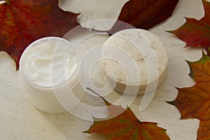 Facial mask and a scrub soap in red maple leaves