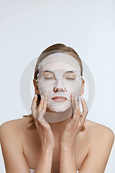 Facial mask. Woman using sheet mask on face skin for spa care