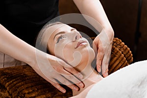 Facial massage close-up in spa center. Girl with perfect skin relaxing in massage room.