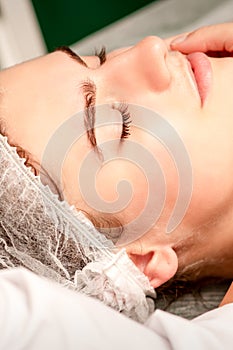 Facial massage. Hands of a masseur massaging neck of a young caucasian woman in a spa salon, the concept of health