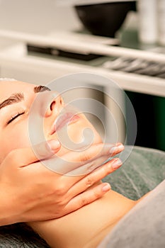 Facial massage. Hands of a masseur massaging neck of a young caucasian woman in a spa salon, the concept of health