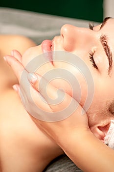 Facial massage. Hands of a masseur massaging neck of a young caucasian woman in a spa salon, the concept of health