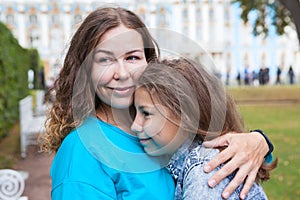 Facial portrait of mother embracing her teenage daughter, Caucasian long hair people, outdoors