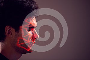 Facial Recognition Technology Concept As Man Has Red Grid Projected Onto Face In Studio