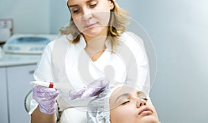 Facial skin care and protection. A young woman at a beautician& x27;s appointment. The specialist applies a cream mask to the