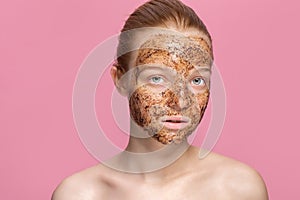 Facial skin scrub Coffee grounds mask on the face of a beautiful young woman Organic natural cosmetology Pink studio