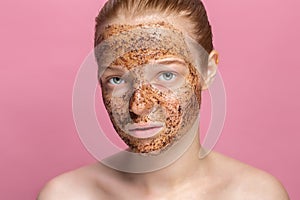 Facial skin scrub Coffee grounds mask on the face of a beautiful young woman Organic natural cosmetology Pink studio