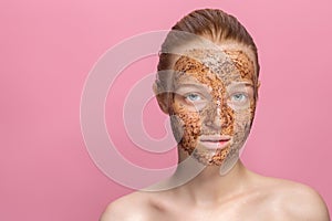 Facial skin scrub Coffee grounds mask on the face of a beautiful young woman Organic natural cosmetology Pink studio