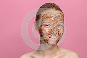 Facial skin scrub Coffee grounds mask on the face of a beautiful young woman Organic natural cosmetology Pink studio