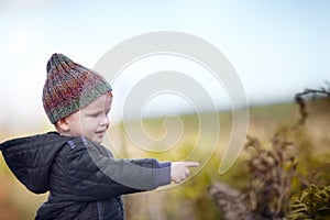 Facinated by nature. A cute little boy pointing at something while outside.