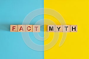 Fact versus myth information concept. Wooden blocks typography in bright blue and yellow background.