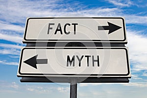 Fact versus myth road sign with two arrows on blue sky background. White two street sign with arrows on metal pole. Two way road