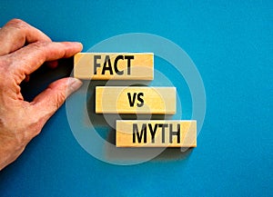 Fact vs myth symbol. Concept words Fact vs myth on wooden blocks on a beautiful blue table blue background. Businessman hand.