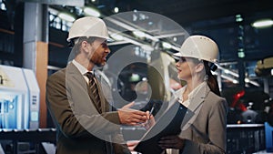 Factory boss making deal shaking hands with woman engineer in helmet close up.