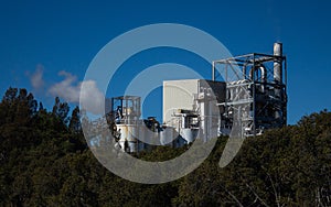 Factory building set on riverbank with steam evaporating to blue sky from chimney