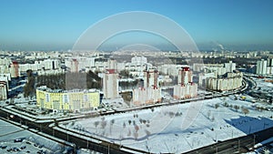 Factory buildings covered with snow. Factory smoke chimneys. There is a railway nearby. You can see the city blocks. Winter