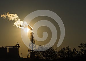 Factory chimney emits or discharges heavy smokes during sunset creating pollution.