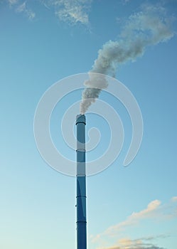A factory chimney with smoke billowing into the air. Large amounts of steam or smoke billowing from an industrial smoke