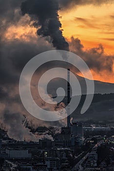 Factory with chimney and smoke and steam with colorful sunset at background