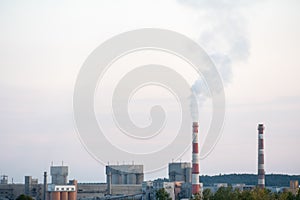 Factory chimneys against the gray autumn sky. Utopian landscape background. White toxic smoke is coming from a huge pipe.