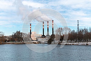 Factory chimneys emit puffs of smoke against the blue sky.