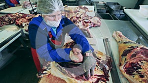 Factory employee is dressing pieces of raw meat