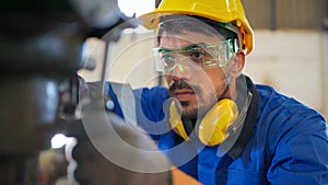 Factory engineer checking or maintenance machine. Wearing safety helmet and glasses to prevent accident. Worker inspector