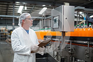 Factory engineer maintaining record on clipboard in factory