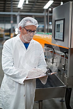 Factory engineer maintaining record on clipboard in factory