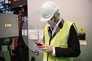 Factory engineer using smartphone at machine