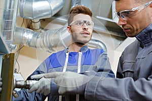 Factory engineers operating hydraulic tube bender