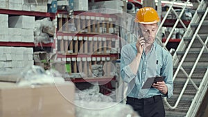 The factory enginner in helmet is checking production and calling