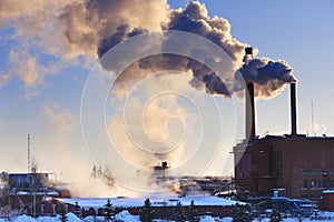 Factory and exhaust fumes blown into a sky.