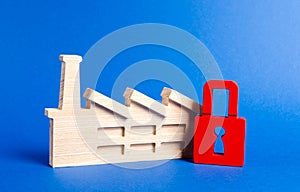 Factory figurine and red padlock. The law on the prohibition of industrial facilities, the closure of harmful production. photo