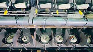 Factory machines spool white threads on clews automatically.