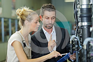 factory manager and apprentice engineer looking at clipboard