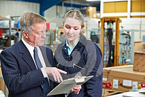 Factory Manager And Apprentice Engineer Looking At Clipboard