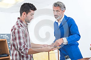 Factory manager and engineering apprentice discussing component