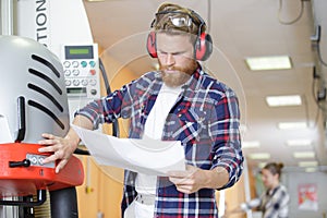 factory operative with paperwork setting up machinery photo